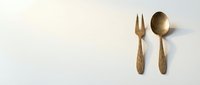 Golden brass serving utensils fork and spoon set on neutral background for kitchen dining and culinary design projects.