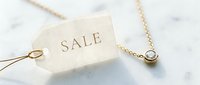 Gold diamond pendant necklace with a sale tag on marble surface, elegant jewelry discount concept for retail and fashion promotion.