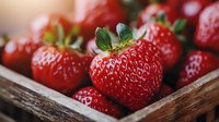 Fresh ripe strawberries with green leaves in rustic wooden box, macro shot showing juicy red fruit texture and natural organic produce.