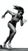 Athletic woman of African descent sprinting off starting block in dynamic running pose for sports training, fitness, and athletic competition concepts.
