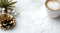 Minimalist coffee scene with latte art heart, golden pinecone decoration and succulent plant on white hexagonal tile surface, modern cafe styling.