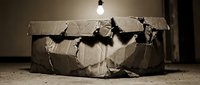 Damaged cardboard box with torn edges and holes in dimly lit room. Concept for shipping problems, package damage, delivery issues, or storage mishaps.