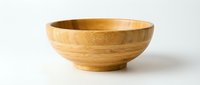 Wooden bamboo bowl isolated on white background, showcasing natural grain texture and eco-friendly craftsmanship for kitchen and food styling use.