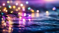 Colorful fairy lights reflecting on wet pavement surface creating magical bokeh effect with purple and blue tones for holiday decorations and celebrations.