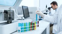 Male scientist in white lab coat conducting chemical analysis with colorful test tubes in modern laboratory setting for research and development.