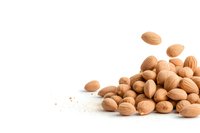 Fresh whole almonds scattered on white background with floating nuts creating dynamic composition, isolated healthy snack for food packaging design.