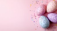 Pastel colored Easter eggs decorated with black dots and confetti on pink background with copy space for holiday greeting design and text.