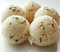 Round white rice balls garnished with fresh chopped chives on white surface, traditional Asian cuisine appetizer showing texture and detail.