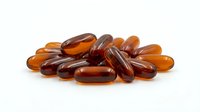Amber colored vitamin capsules and supplements scattered on white background for health and wellness marketing materials.