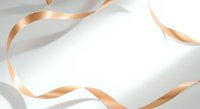 Blank white card with flowing golden ribbons on neutral background, suitable for greeting cards, invitations, and promotional designs.