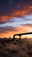 Industrial pipeline infrastructure against dramatic sunset sky with orange and purple clouds over desert landscape for energy sector projects.