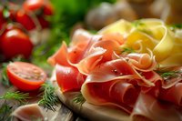 Sliced prosciutto ham with fresh herbs, cherry tomatoes and cheese on wooden board. Gourmet Italian appetizer platter for restaurant menu or cooking blog.