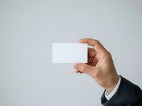 Man holding blank white business card in hand against neutral background. Professional male displaying empty card for corporate branding and identity design.