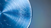 Blue metallic surface with circular brushed texture and fine scratches creating industrial pattern for modern design backgrounds.