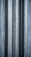 Weathered gray metal fence panels with vertical ridges and rust spots creating industrial texture for construction and urban design backgrounds.