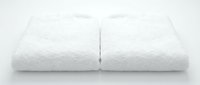 Two clean white fluffy terry towels folded and stacked on white background, isolated for spa, hotel, bathroom and hygiene design use.