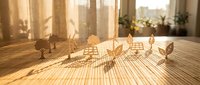 Wooden eco-friendly house models with leaf symbols on table in warm sunlight, representing sustainable architecture and green building concepts.