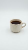 Rustic cream ceramic mug filled with dark coffee or tea, isolated on white background. Vintage-style cup suitable for beverage, kitchen, and lifestyle design projects.