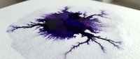 Ink splatter with branching tendrils spreading across white paper surface, creating organic abstract pattern with deep purple and black tones for artistic and creative projects.