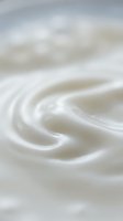Creamy white swirl texture with smooth flowing curves and soft bokeh background for cosmetic and skincare product design applications.