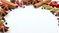 Aromatic spices and herbs frame creating copy space on white background for culinary designs, cooking recipes, and food photography projects.