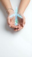 Female hands holding glowing blue crystal formation with protective gesture on white background for spiritual healing and energy concepts.