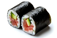 Fresh tuna roll sushi with cucumber, rice wrapped in nori seaweed on white background, traditional Japanese cuisine preparation shown in macro detail.