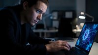 Focused businessman working late at night on laptop with data visualization in modern office environment for productivity and technology concepts.