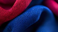 Vibrant red and blue textured fabric waves create dynamic abstract pattern with soft curves and detailed mesh structure, showcasing modern sportswear material.