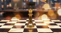 Golden chess king piece standing on checkered board with warm bokeh lights creating strategic business leadership concept for corporate presentations.