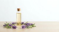 Essential oil bottle with cork stopper surrounded by fresh lavender flowers on wooden surface for aromatherapy and natural wellness products.