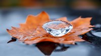 Crystal clear water droplet resting on vibrant orange autumn maple leaf against dark background, showcasing nature's delicate balance.