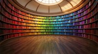 Circular library with rainbow-colored books arranged on curved shelves under skylight dome, wooden floor, knowledge and learning concept for education.