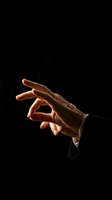 Elegant male hand making OK gesture against black background with dramatic lighting for business success and approval concepts.