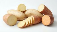 Fresh organic sweet potatoes with sliced pieces showing orange flesh, isolated on white background for healthy cooking and nutrition designs.