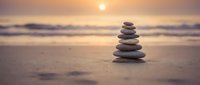 Zen stone stack on beach at sunset creating peaceful meditation scene with golden light and ocean waves for wellness and mindfulness concepts.