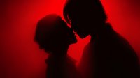 Romantic couple silhouettes in intimate moment against dramatic red lighting background for Valentine's Day, love and relationship concepts.
