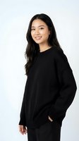 Young Asian woman in black sweater smiling at camera on white background. Studio portrait for fashion, lifestyle and commercial projects.