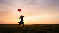 Woman in silhouette running through open field at sunset holding red balloon, symbolizing freedom, hope, and aspirational lifestyle for motivational and wellness content.