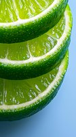 Fresh lime slices stacked in macro view showing juicy pulp and textured green peel against blue background, suitable for food and beverage marketing.