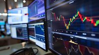 Multiple trading monitors displaying financial charts, stock market graphs and candlestick patterns in dark trading room, perfect for business and investment concepts.
