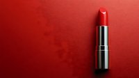Red lipstick on red background with dramatic lighting and shadow effect creates bold minimalist composition for beauty and cosmetic advertising.