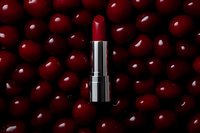 Red luxury lipstick on dark cherry background with glossy metallic tube and rich burgundy color for cosmetic and beauty advertising campaigns.
