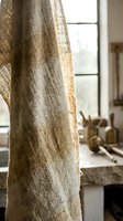 Natural linen curtain hanging in sunlit kitchen window with rustic cooking utensils and wooden bowls on counter creating warm homey atmosphere for interior design.