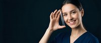 Young professional woman talking on smartphone with confident smile against dark background for business communication concepts.