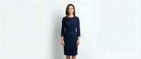 Young woman with long dark hair and fair complexion wearing a navy blue long-sleeved knee-length dress, standing against white background for fashion and apparel design use.