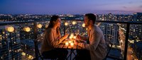 Young couple enjoying romantic dinner on rooftop terrace with city lights and candles at twilight creating intimate atmosphere for date night celebration.