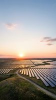 Aerial view of expansive solar panel farm at sunset with rows of photovoltaic arrays stretching across rural landscape, renewable energy generation and sustainable power infrastructure.