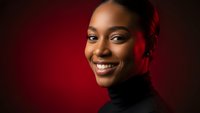 Professional African American businesswoman smiling confidently against red background for corporate marketing and diversity campaigns.