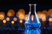 Laboratory flask containing luminescent blue liquid against dark background with golden bokeh lights, creating magical scientific atmosphere. Suitable for research concepts.